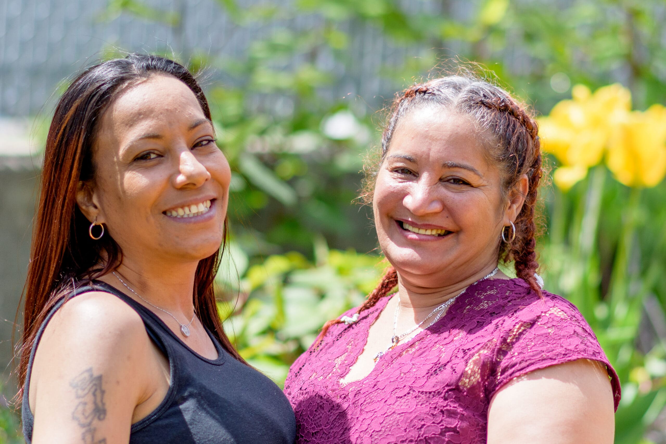 Two smiling women standing together outdoors, representing the supportive, bilingual, and culturally-inclusive services provided by Casa Esperanza, Inc